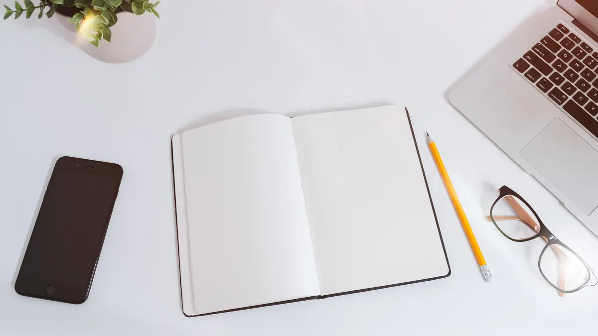 A work table with notes, a phone and a laptop
